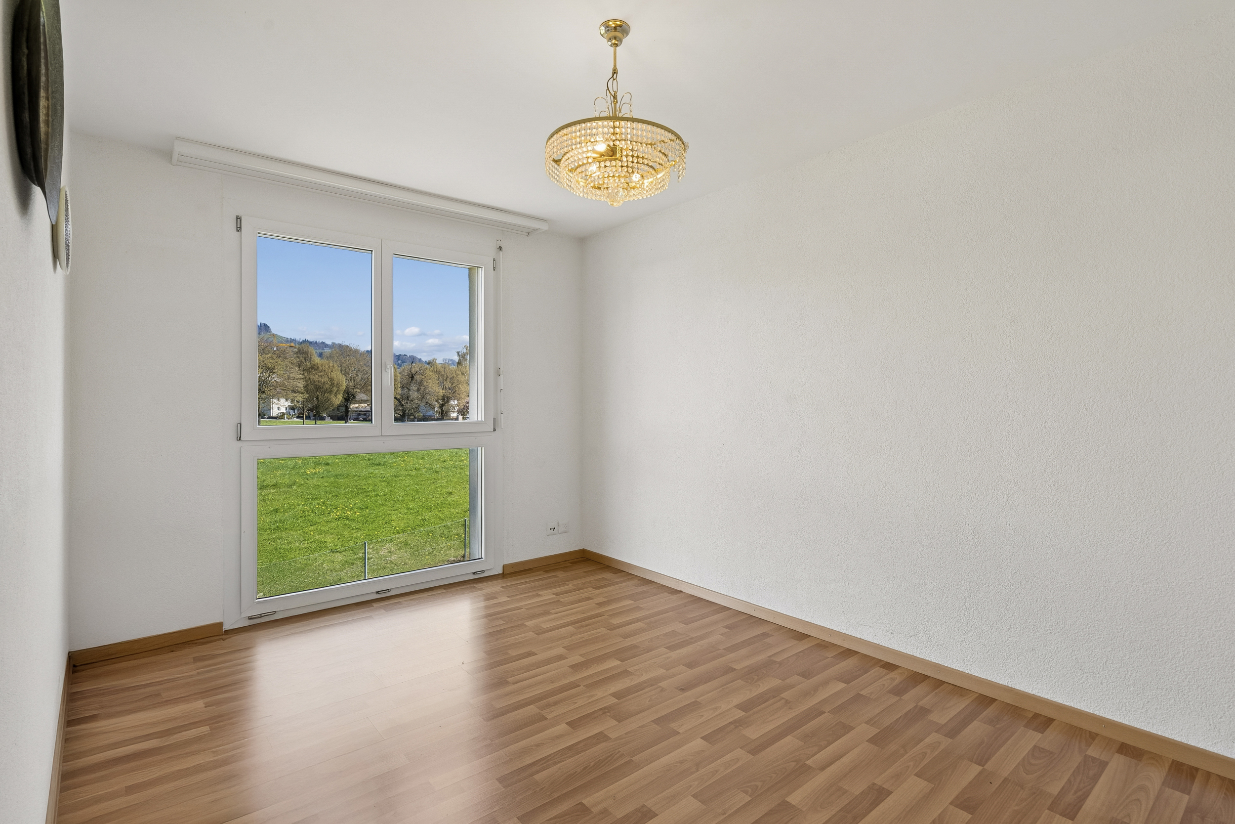 Heller leerer Raum mit großem Fenster und Kronleuchter
