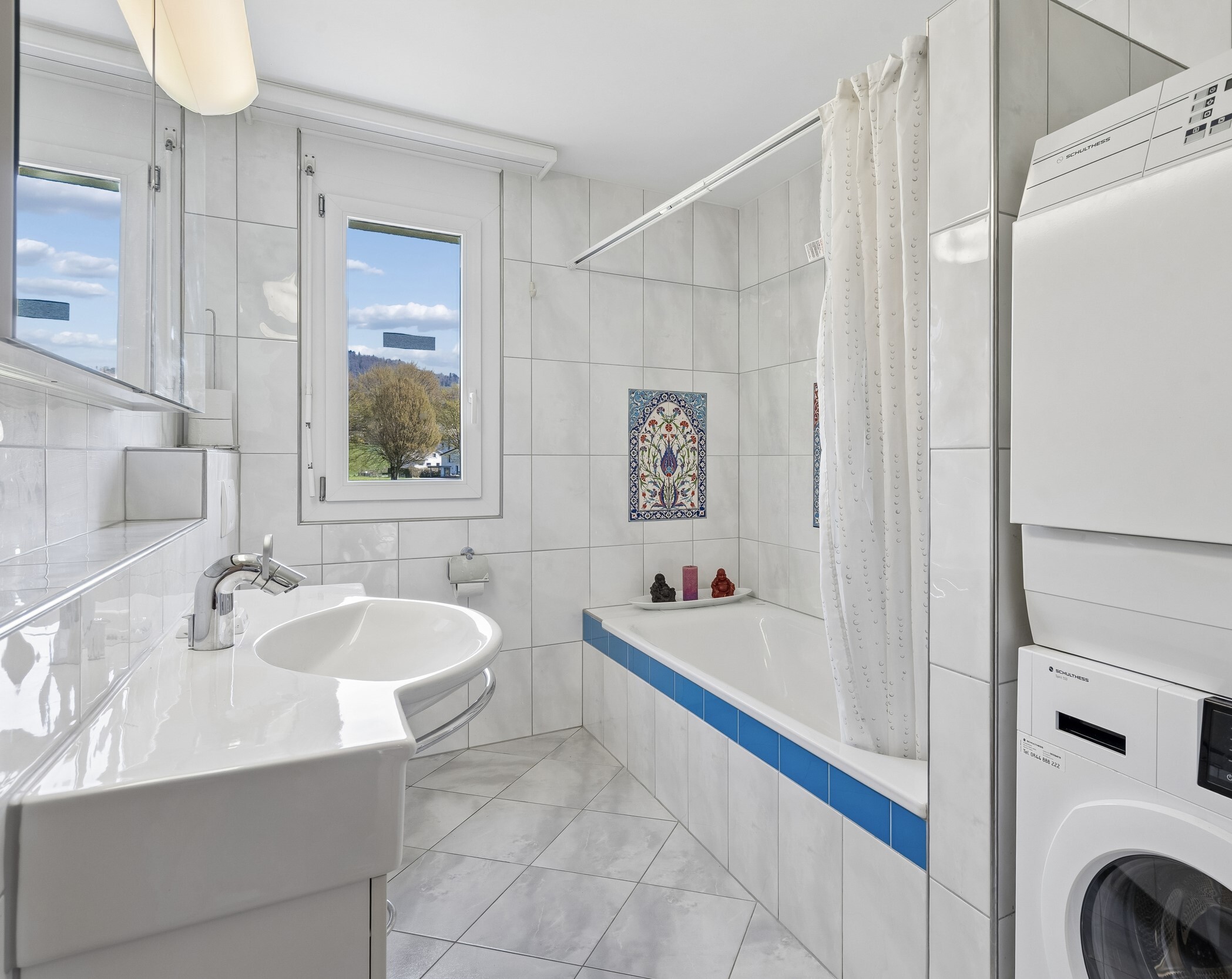 Helles Badezimmer mit Badewanne und Fensterblick
