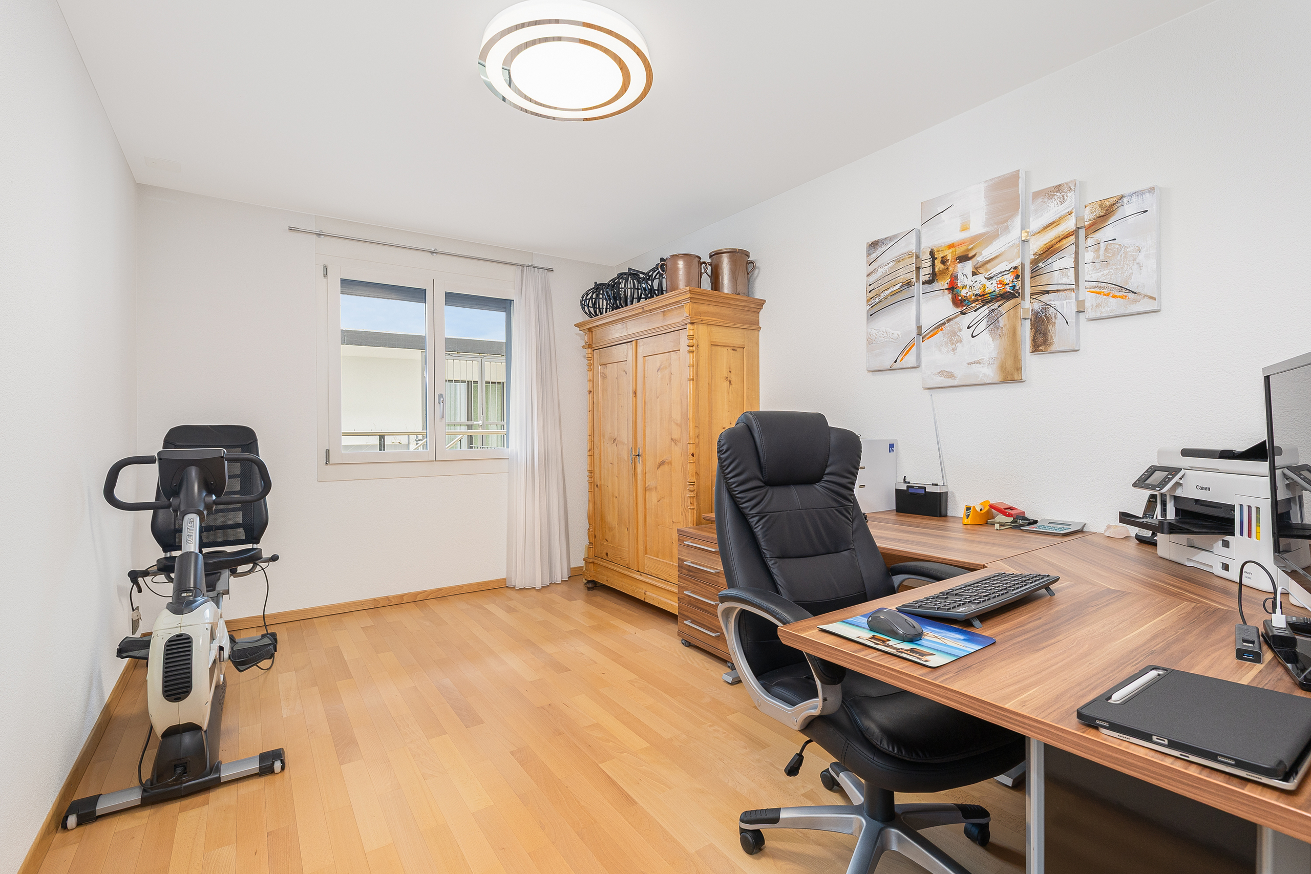 Helles Arbeitszimmer mit Schreibtisch und Heimtrainer