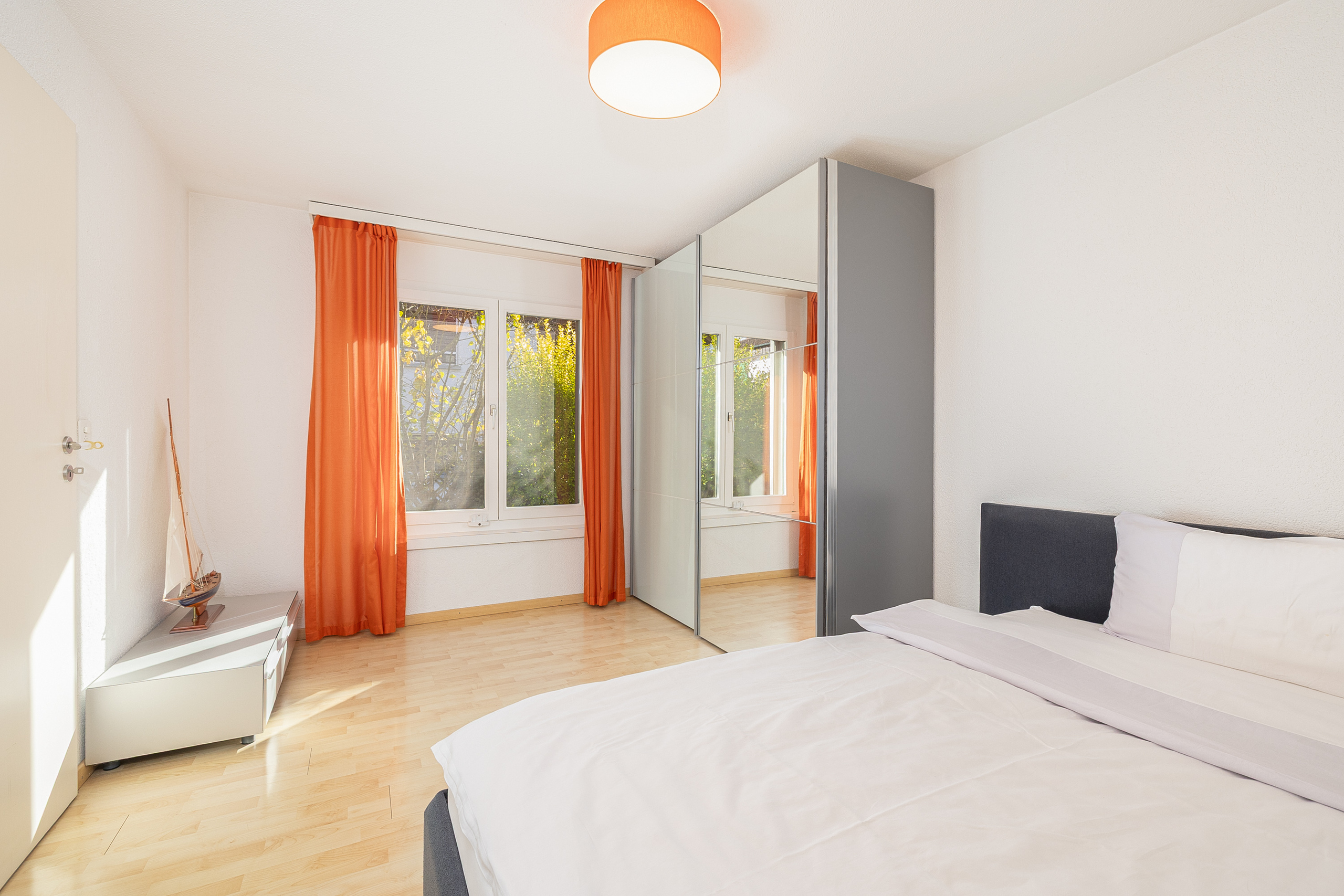 Helles Schlafzimmer mit orangefarbenen Vorhängen
