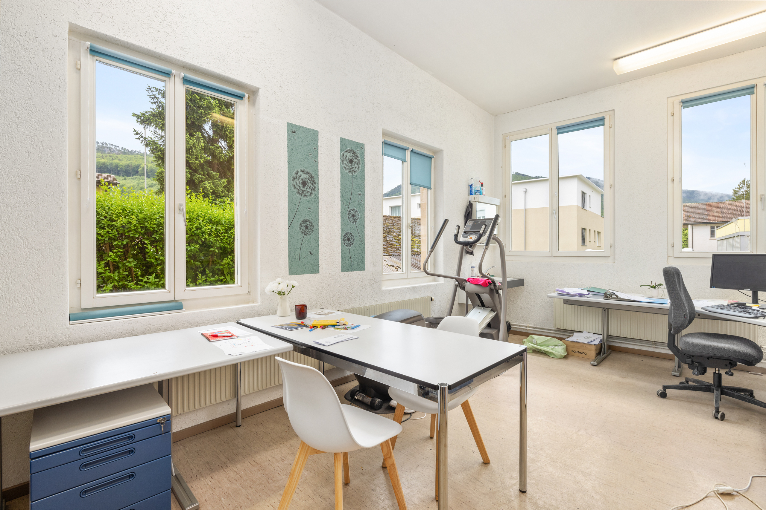 Helles Büro- oder Behandlungszimmer mit großen Fenstern