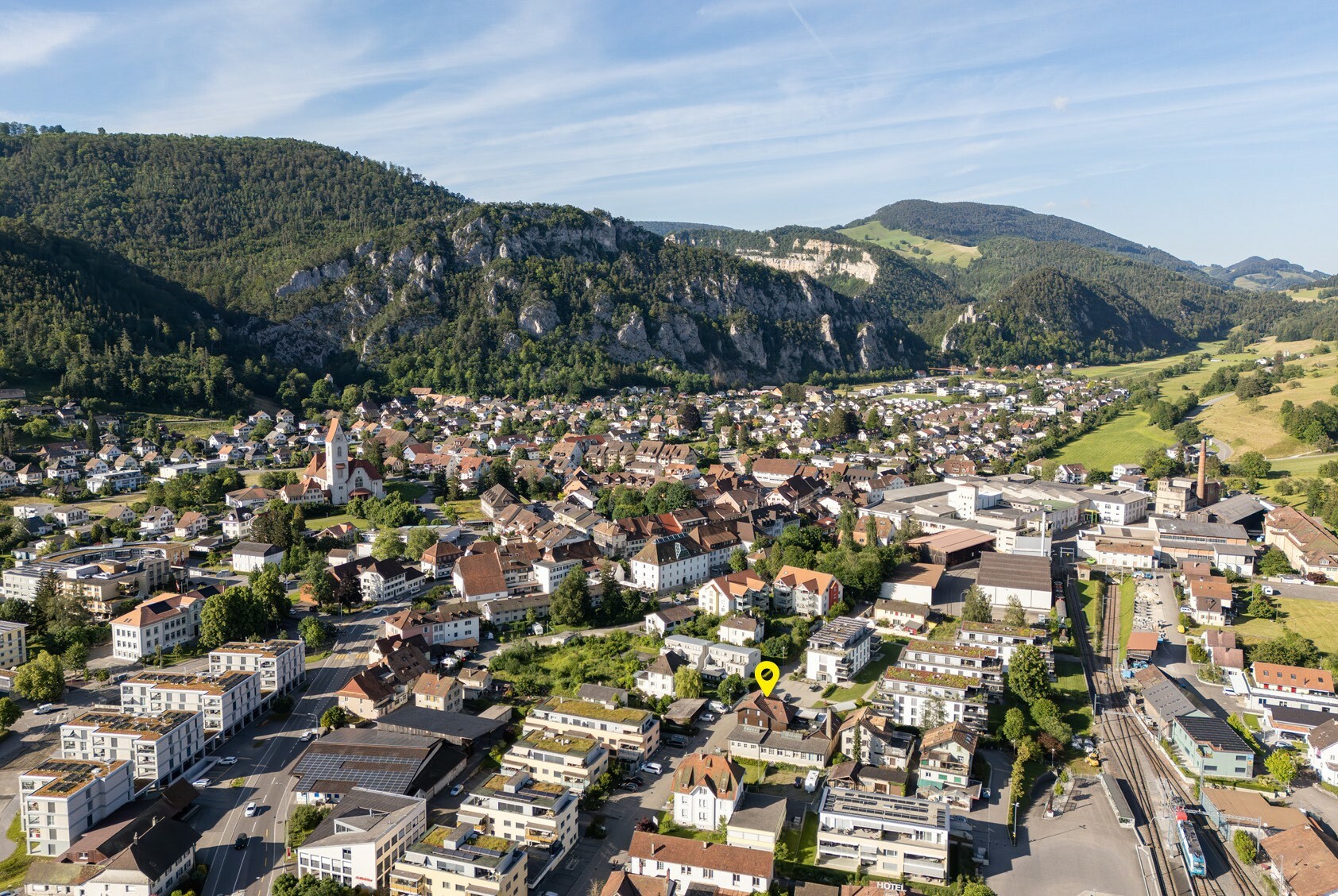 Luftaufnahme einer Stadt im Tal mit Bergen im Hintergrund