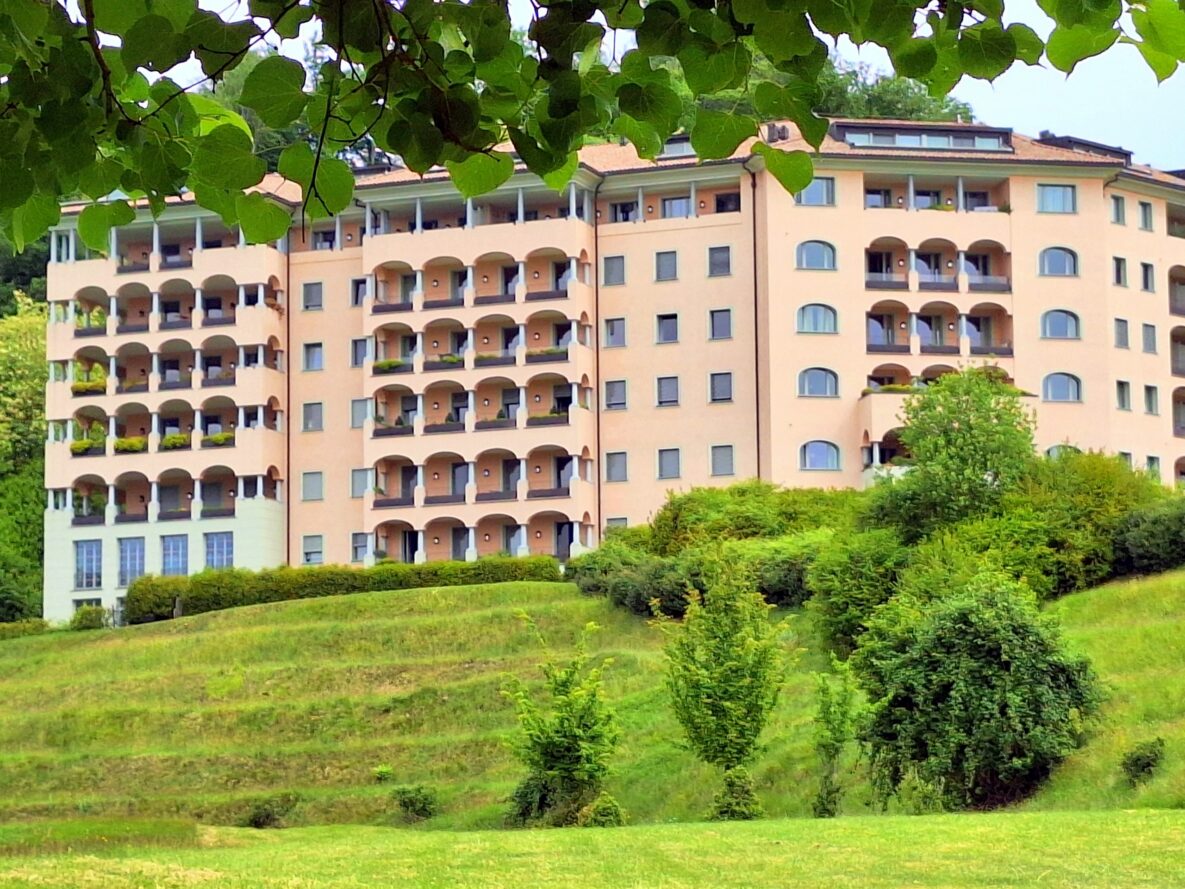 Mehrstöckiges Wohngebäude mit Balkonen in grüner Hanglage