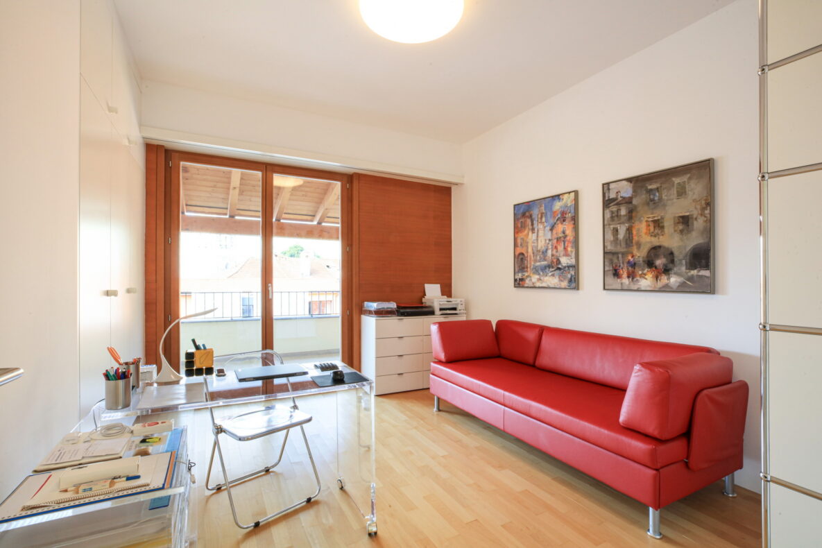 Helles Arbeits- und Wohnzimmer mit rotem Sofa