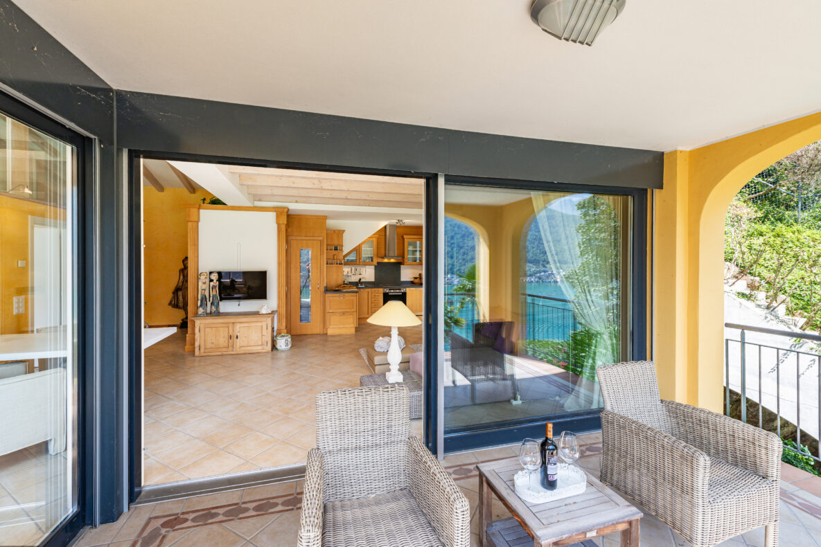 Überdachte Terrasse mit Blick in Wohnbereich und aufs Wasser