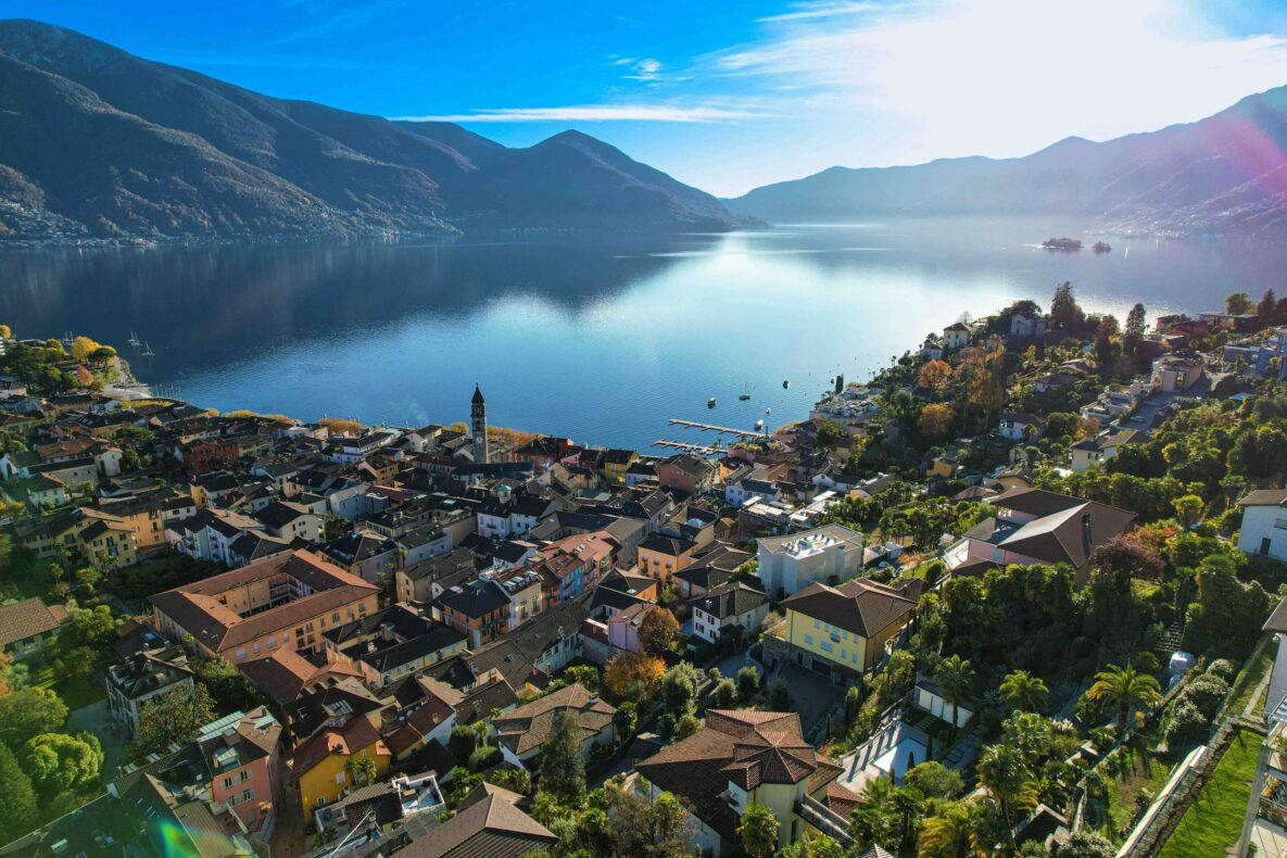 Luftaufnahme einer Stadt am See mit Bergkulisse