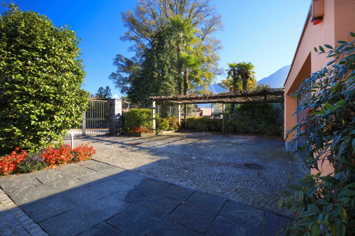 Sonniger Vorplatz mit Garten und Pergola