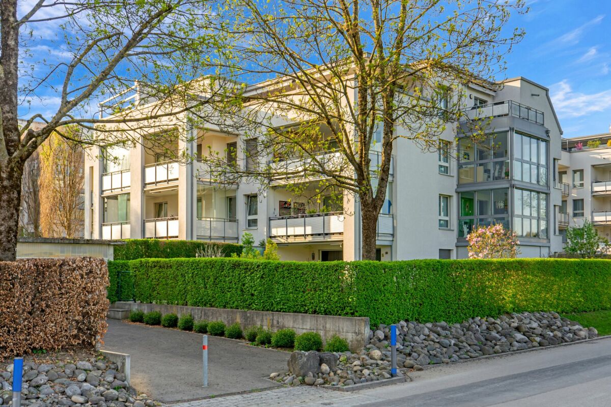 Mehrfamilienhaus mit Balkonen und grüner Umrandung