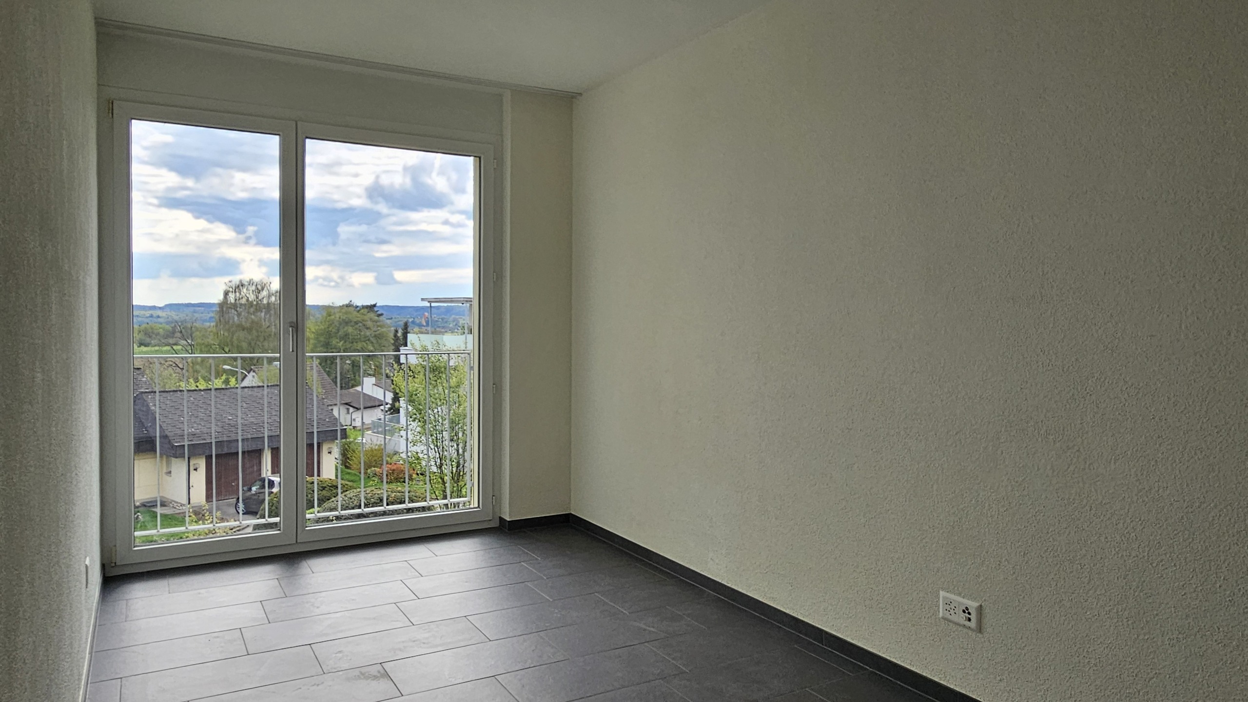 Leerer heller Raum mit Balkon- oder Terrassentür und Ausblick