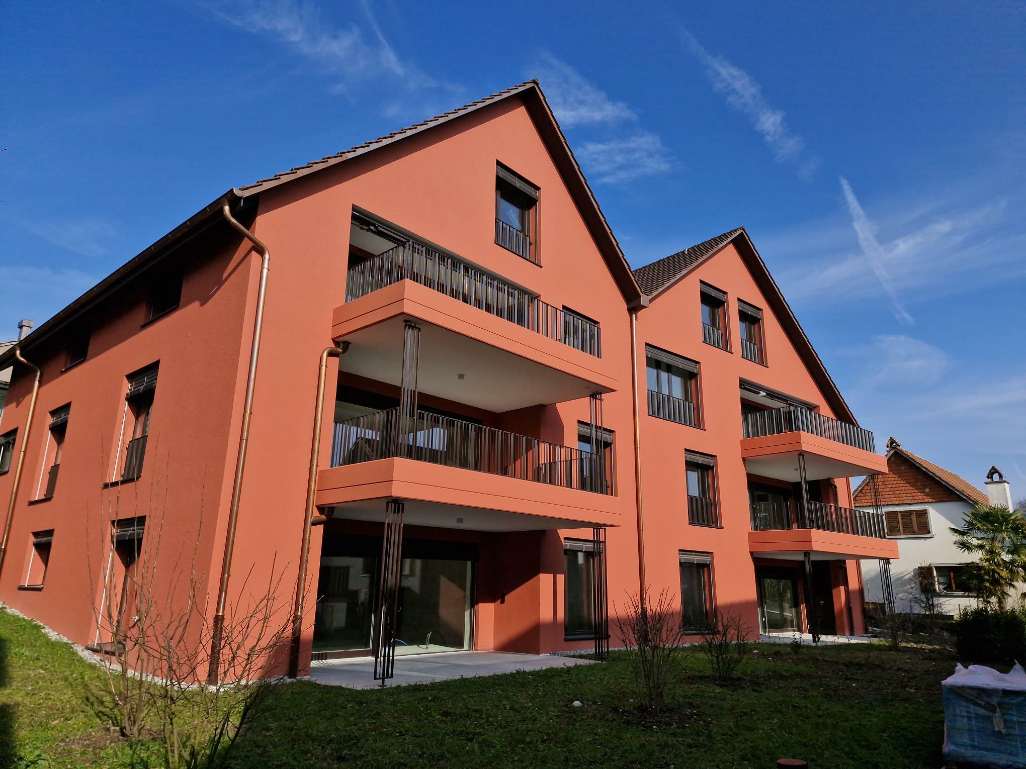 Mehrfamilienhaus mit roten Fassaden und Balkonen
