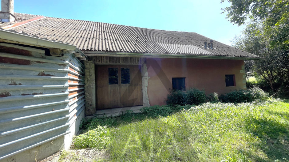 Außenansicht eines niedrigen Hauses mit verwildertem Garten