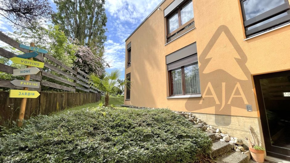 Hausfassade mit Gartenweg und Hinweisschild