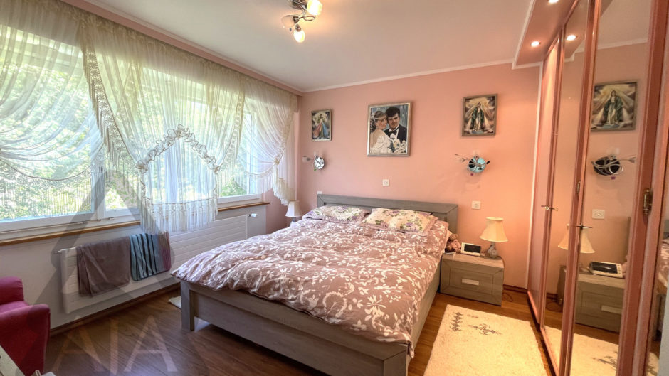Helles Schlafzimmer mit großem Fenster und Spiegelkleiderschrank