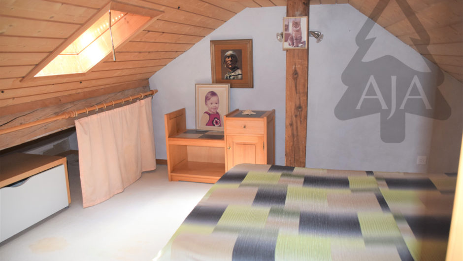 Dachzimmer mit Bett und Holzverkleidung