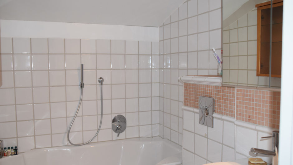 Badezimmer mit Badewanne und großflächigen Fliesen