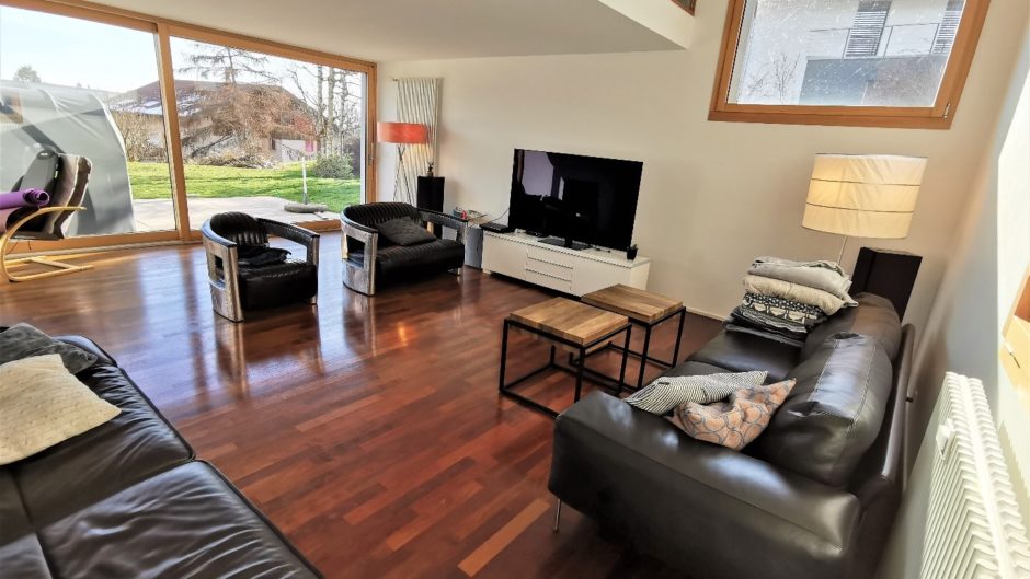 Helles Wohnzimmer mit dunklen Ledermöbeln und Holzboden