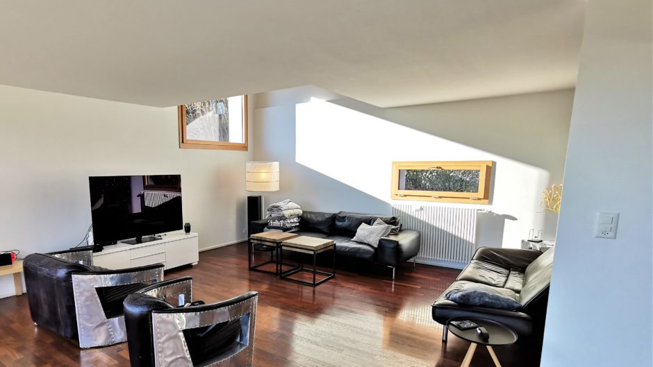 Helles Wohnzimmer mit dunklen Sofas und großem TV