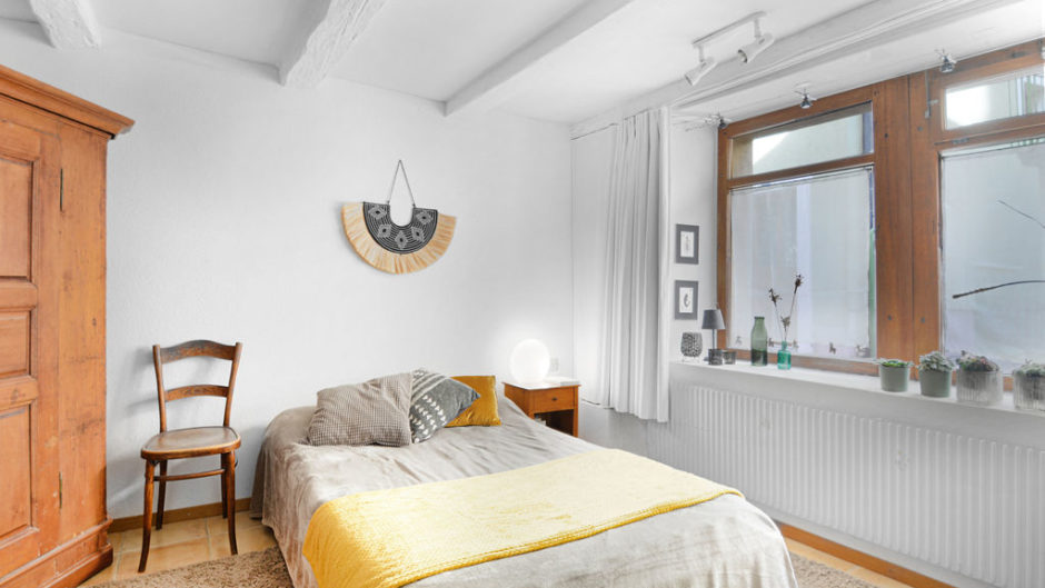 Helles Schlafzimmer mit Holzmöbeln und großem Fenster
