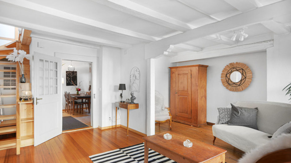 Heller Wohnraum mit Holzboden und angrenzendem Esszimmer