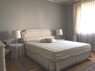 Helles Schlafzimmer mit klassischem Bett und Vorhängen
