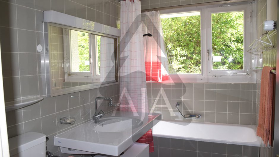 Badezimmer mit Wanne und Fensterblick ins Grüne
