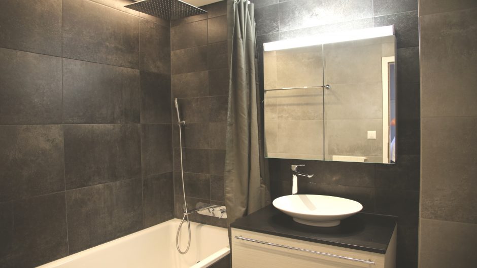Modernes Badezimmer mit dunkler Wandverkleidung und Waschplatz