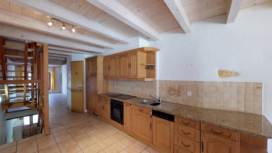 Küche mit Holzdeckenbalken und Treppe