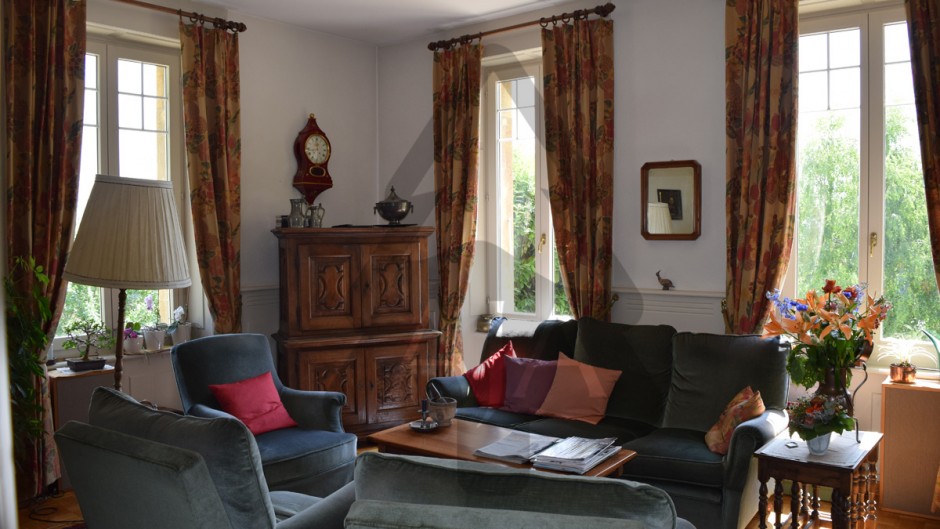 Wohnzimmer mit klassischen Möbeln und großen Fenstern