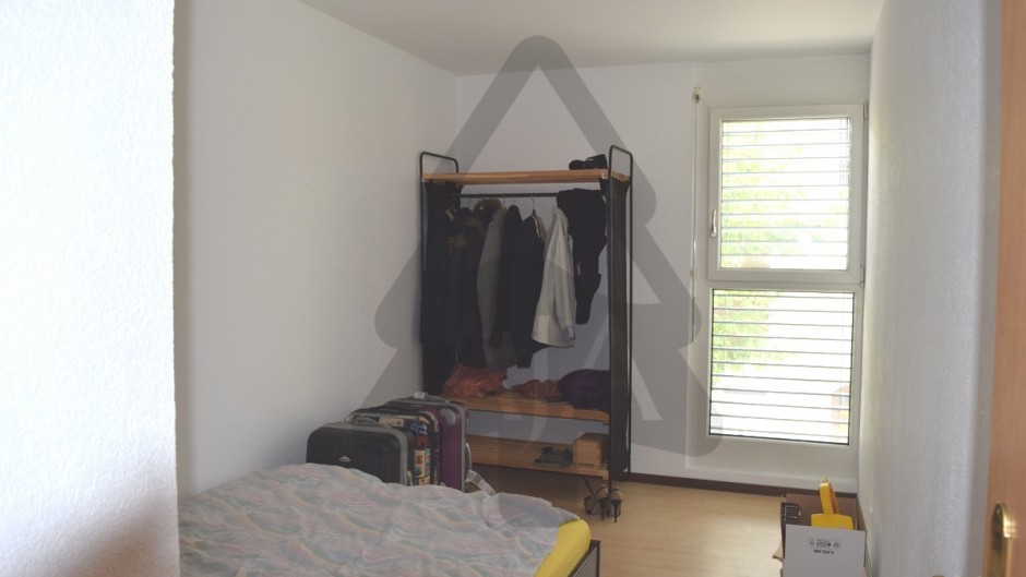 Schlafzimmer mit Kleiderständer und Fenster