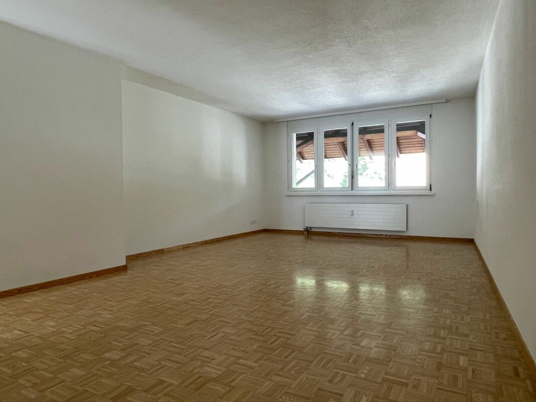 Leerer Wohnraum mit Parkett und Fenster