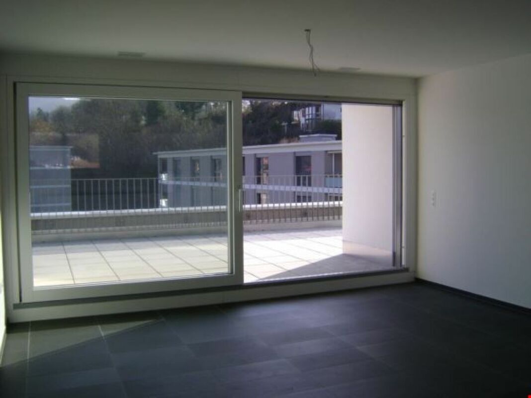 Leerer Wohnraum mit großer Schiebetür zur Terrasse
