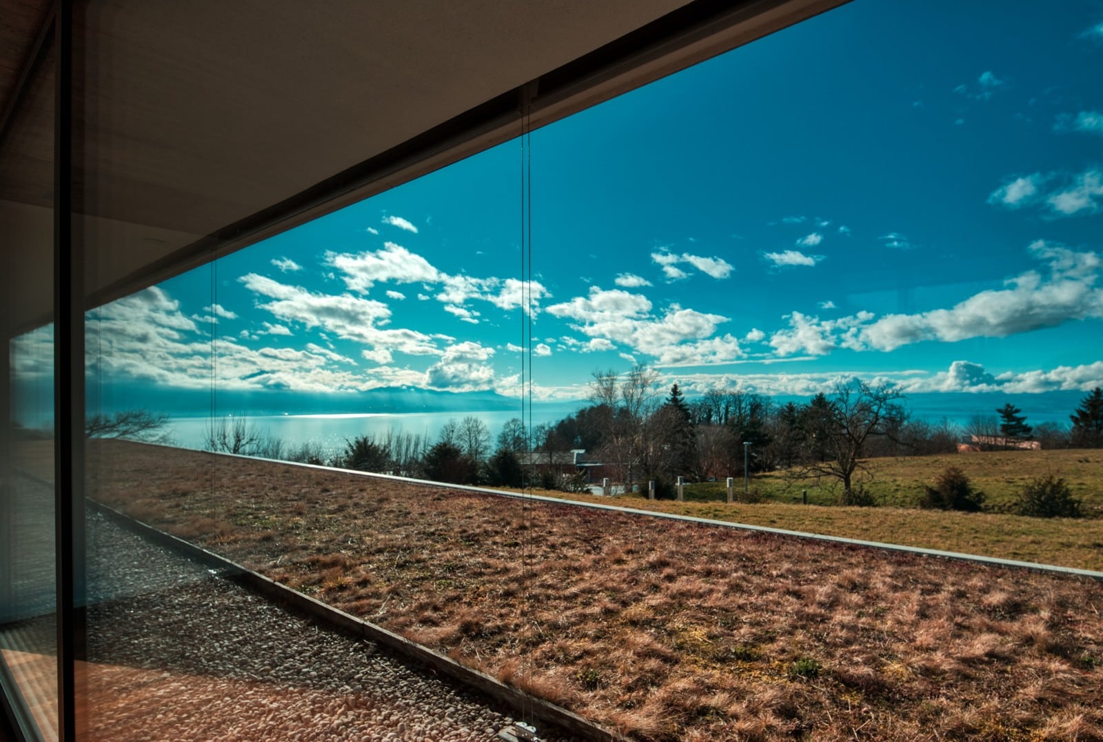 Blick durch große Fenster auf Wasser und Landschaft