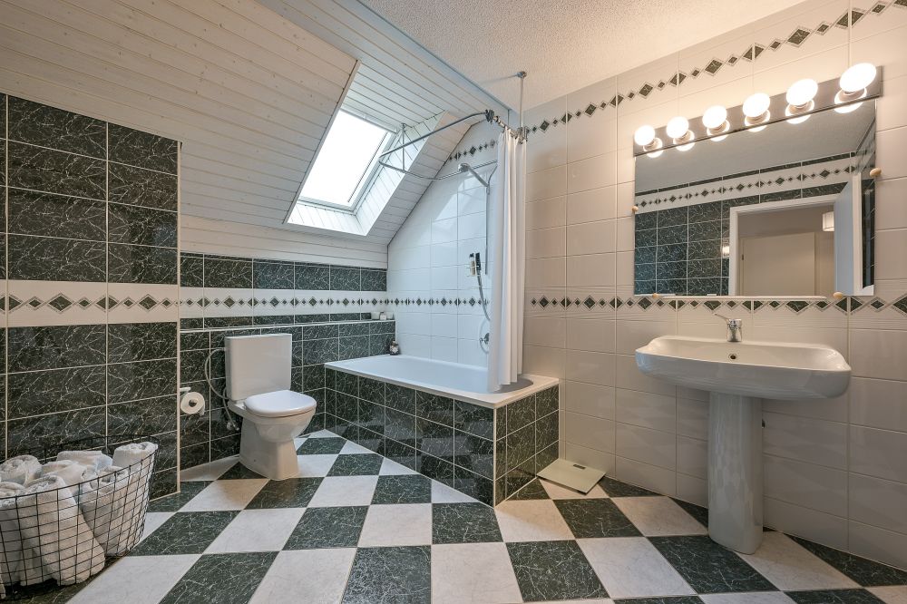 Badezimmer mit Dachfenster und grün-weißer Fliesenoptik