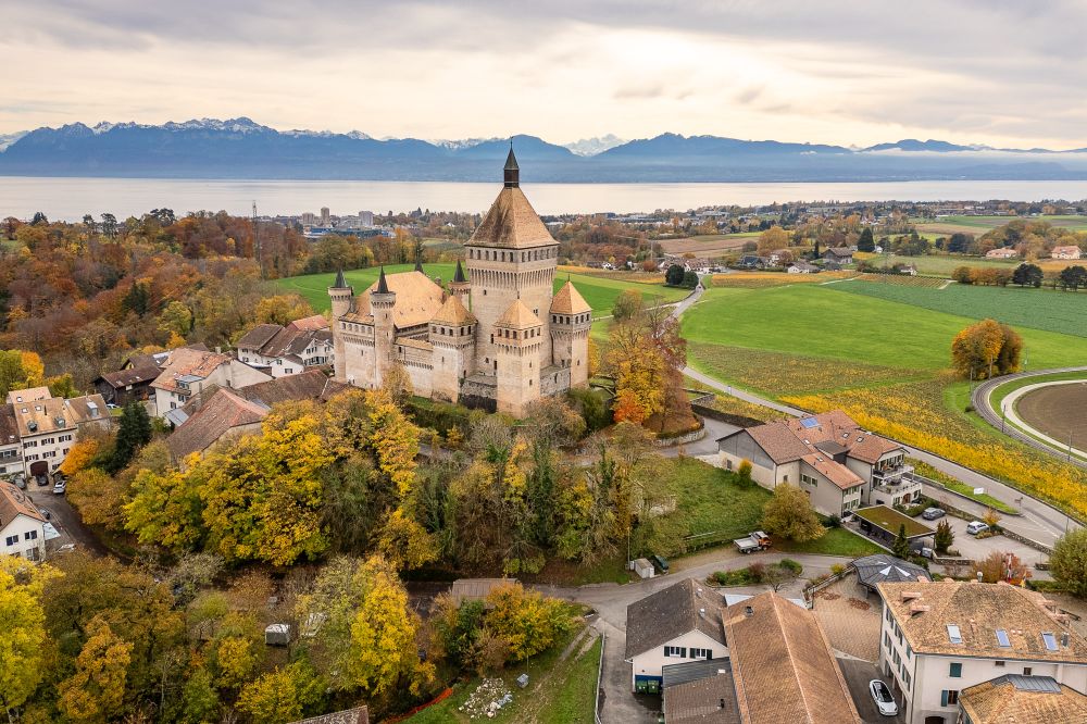 Luftaufnahme einer Burg mit See- und Alpenpanorama