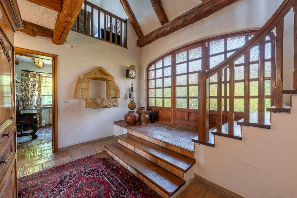 Rustikaler Eingangsbereich mit Holztreppe und großen Fenstern