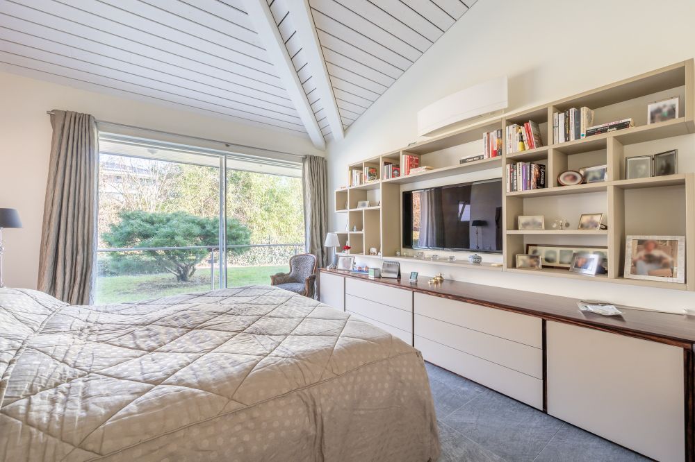 Helles Schlafzimmer mit hoher Decke und Blick in den Garten