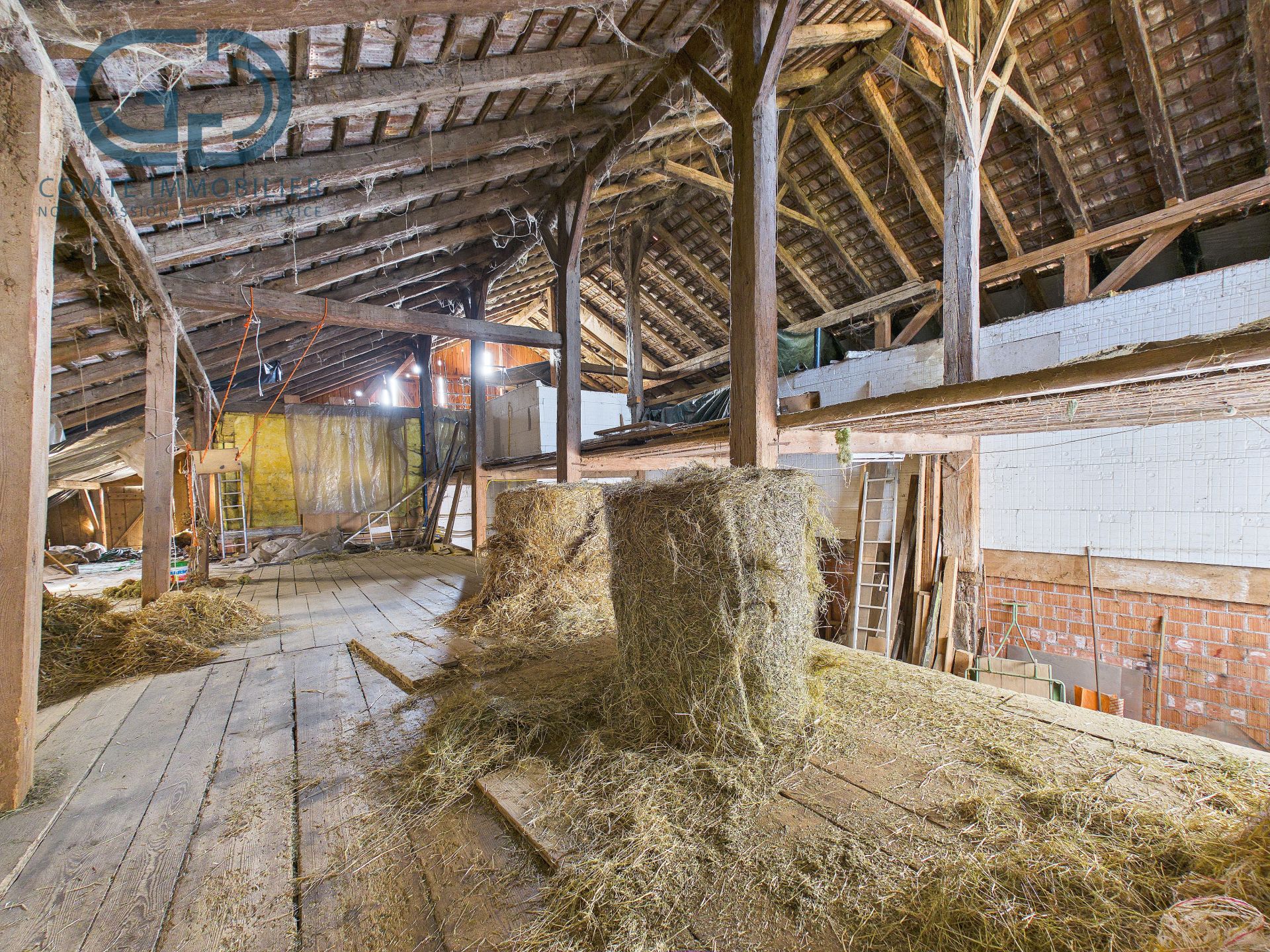 Dachboden im Rohbau mit Heu und sichtbarer Holzkonstruktion