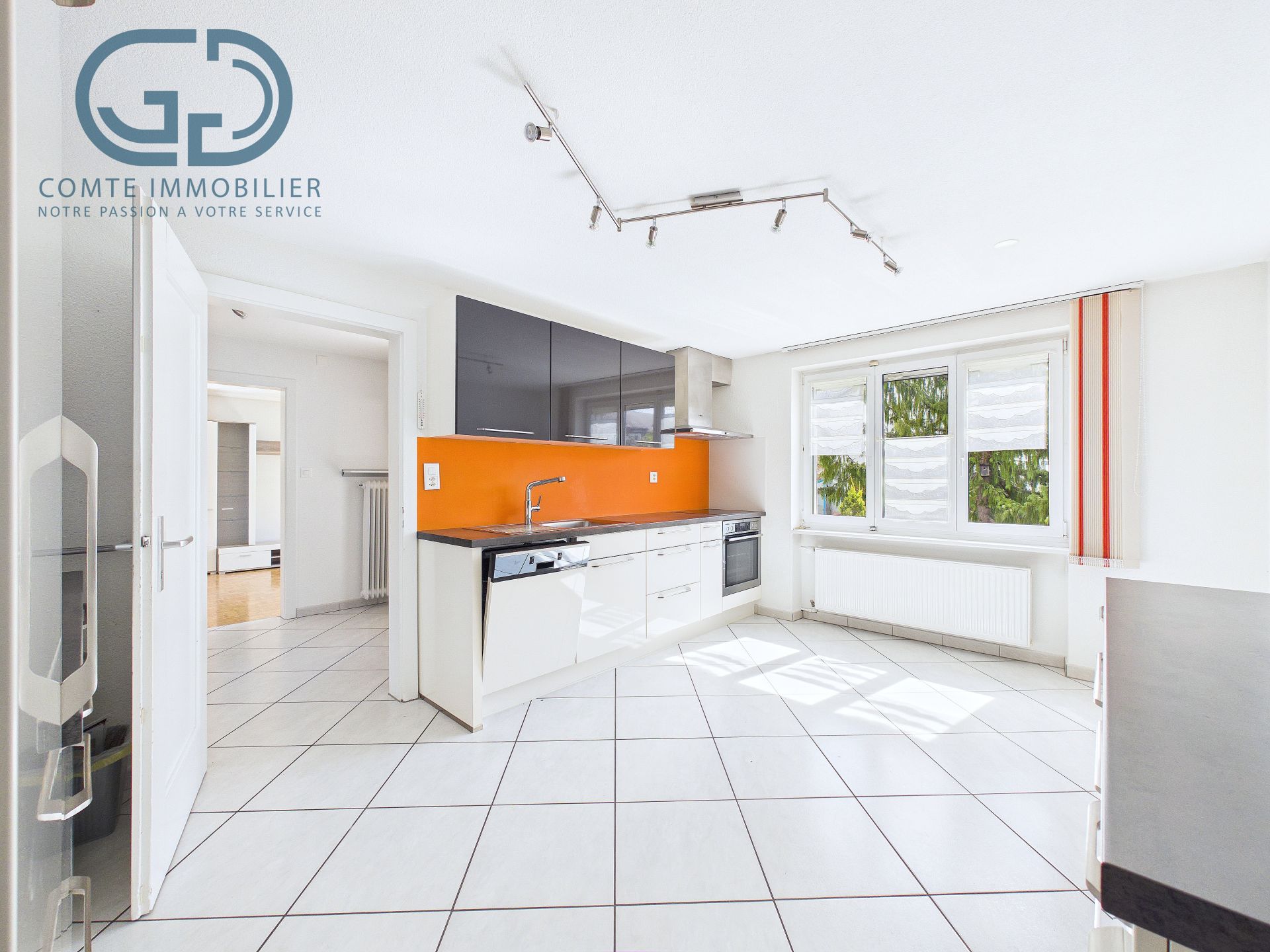 Helle moderne Küche mit Fenster und orangefarbener Rückwand