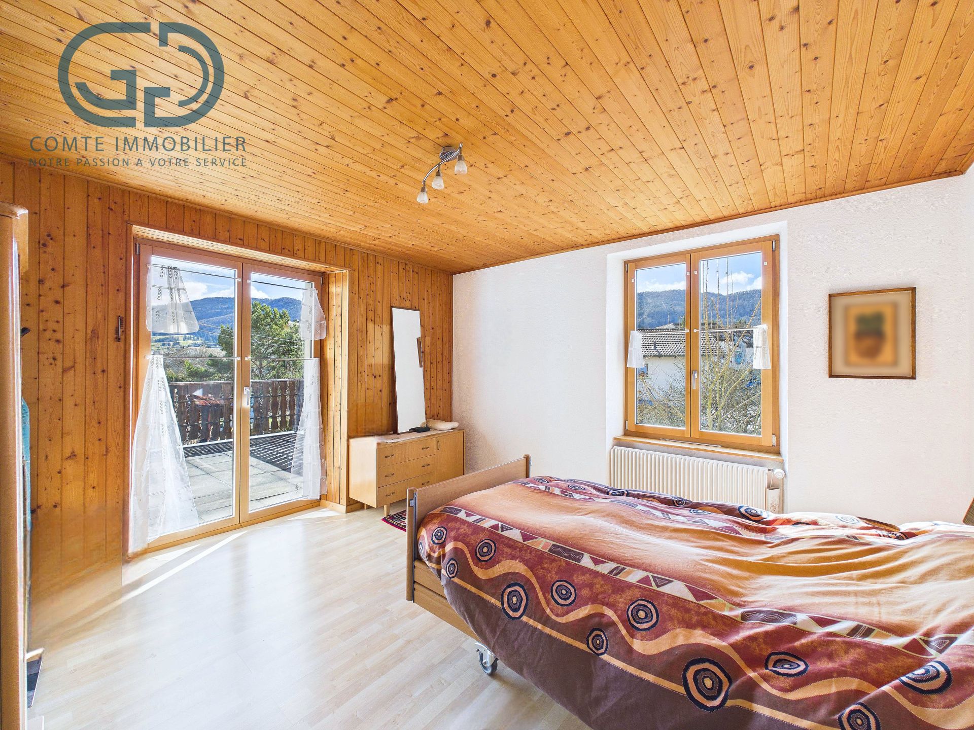 Helles Schlafzimmer mit Holzverkleidung und Balkonzugang