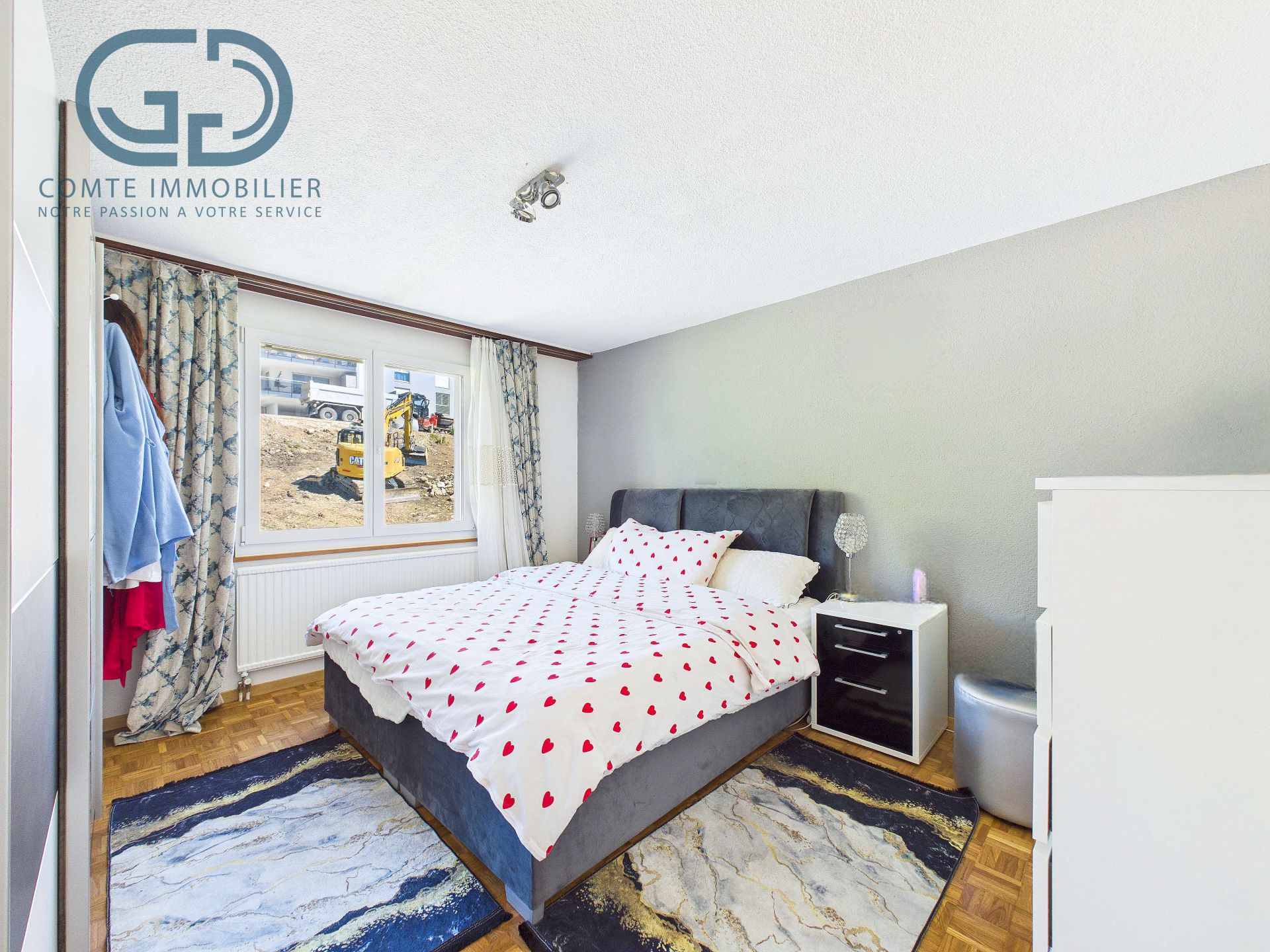 Schlafzimmer mit Doppelbett und Fensterblick auf eine Baustelle