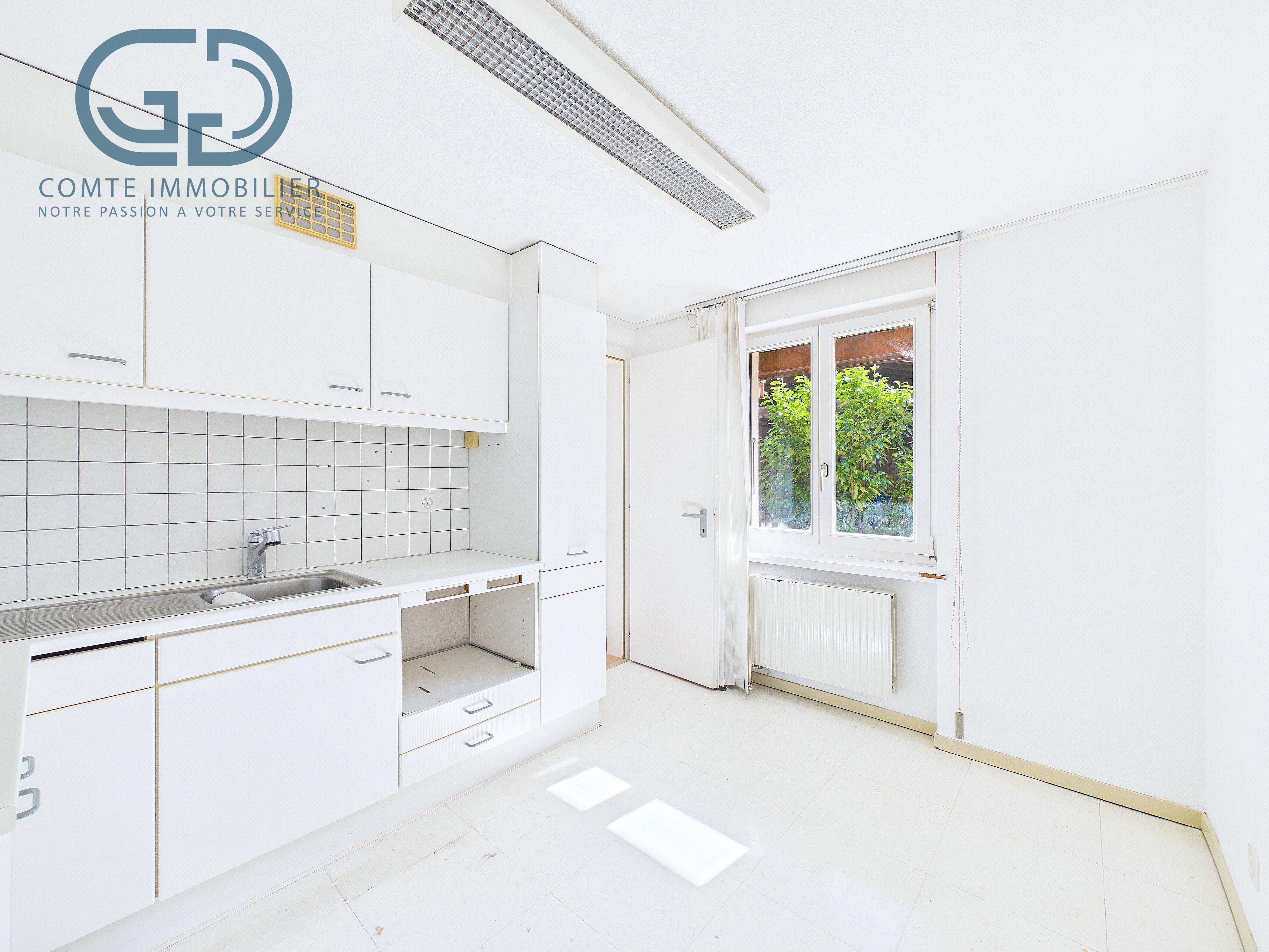 Helle, einfache Küche mit Fenster und weißen Einbauten