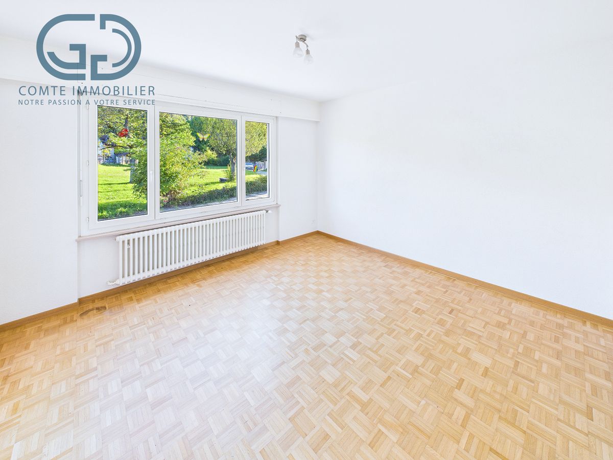 Heller leerer Wohnraum mit Parkett und großem Fenster