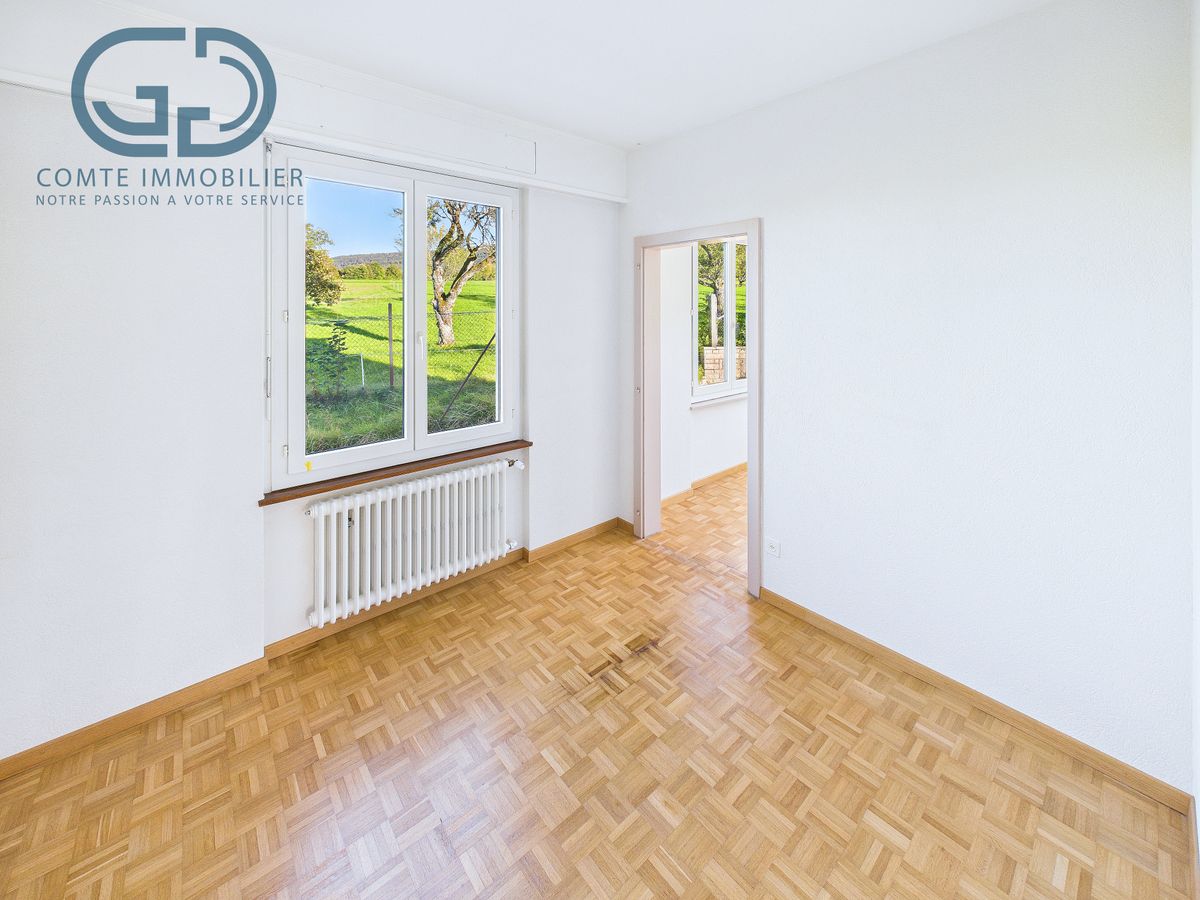 Heller leerer Raum mit Parkett und Fensterblick ins Grüne