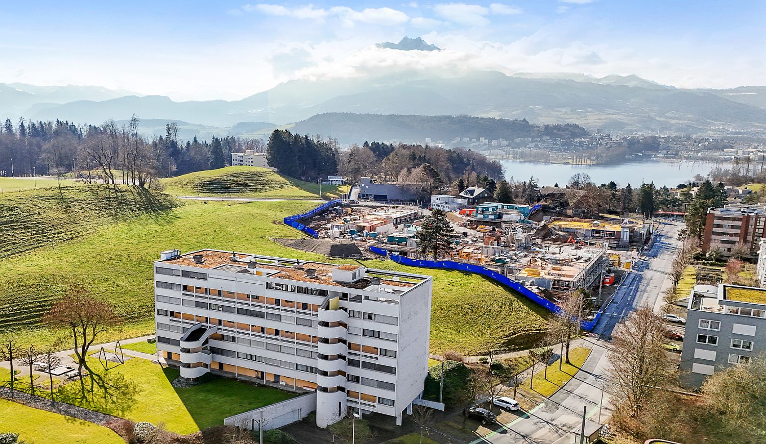 Luftaufnahme eines Wohn- und Bauareals am See mit Bergkulisse