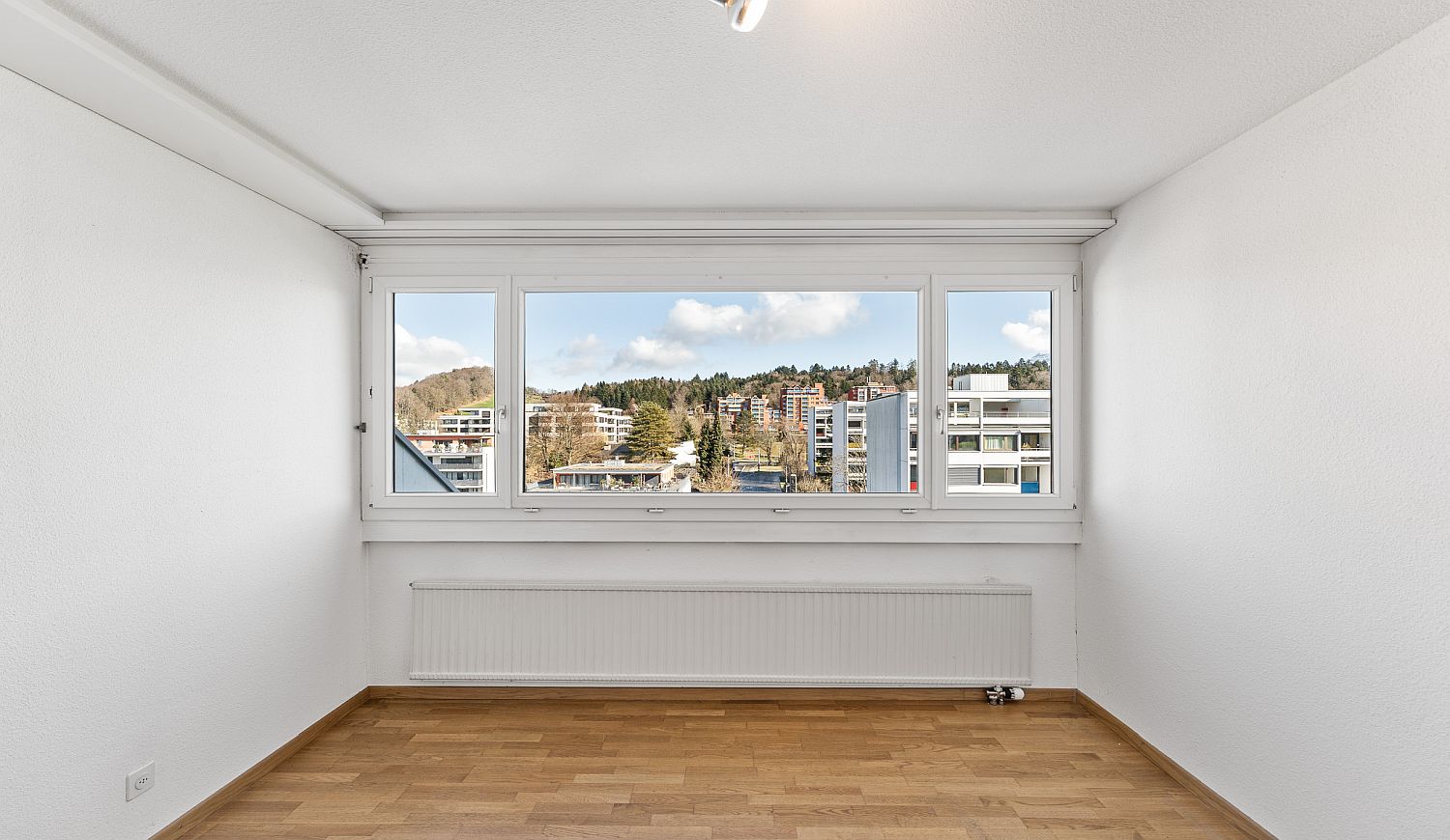 Leerer heller Raum mit großem Fenster und Blick ins Grüne