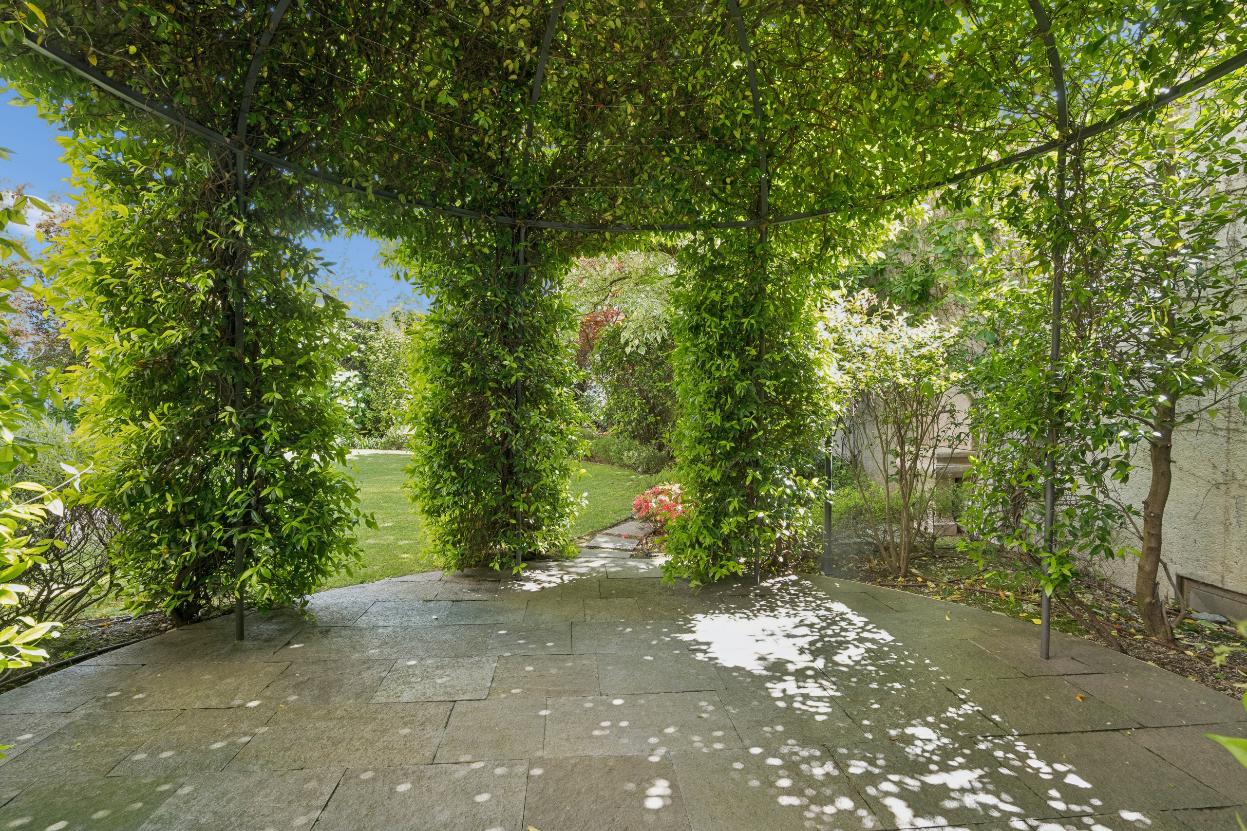 Überdachte Gartenpergola mit üppiger Begrünung