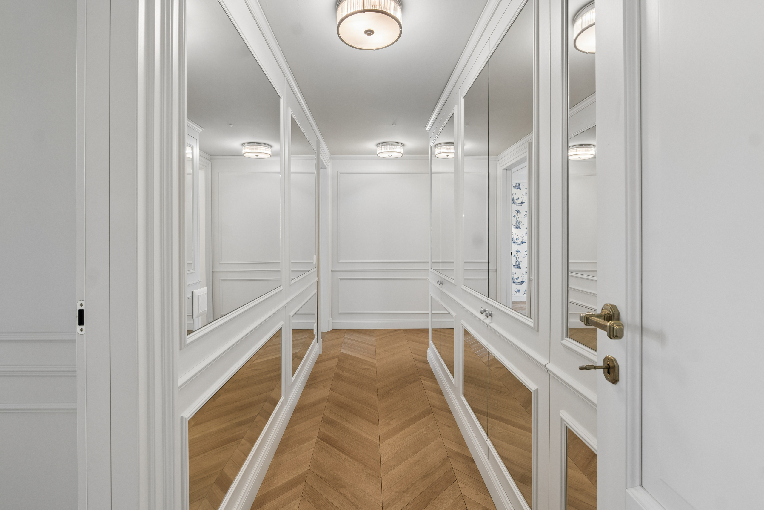 Eleganter begehbarer Ankleideflur mit Spiegelschrank und Fischgrätparkett