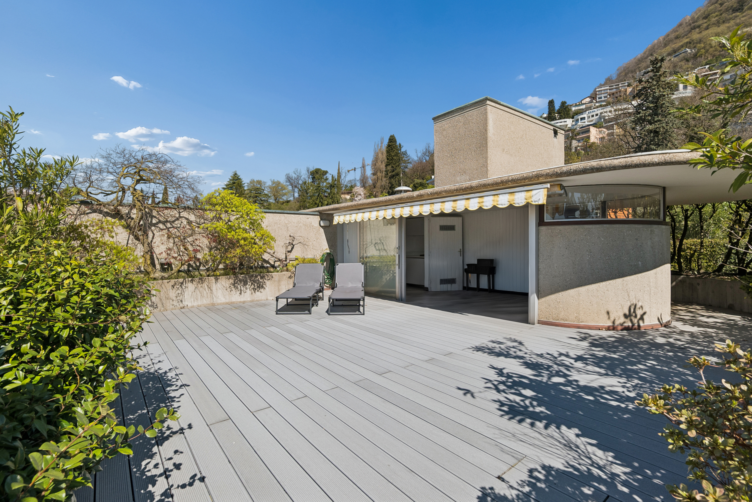 Große Dachterrasse mit Liegen und Gartenblick