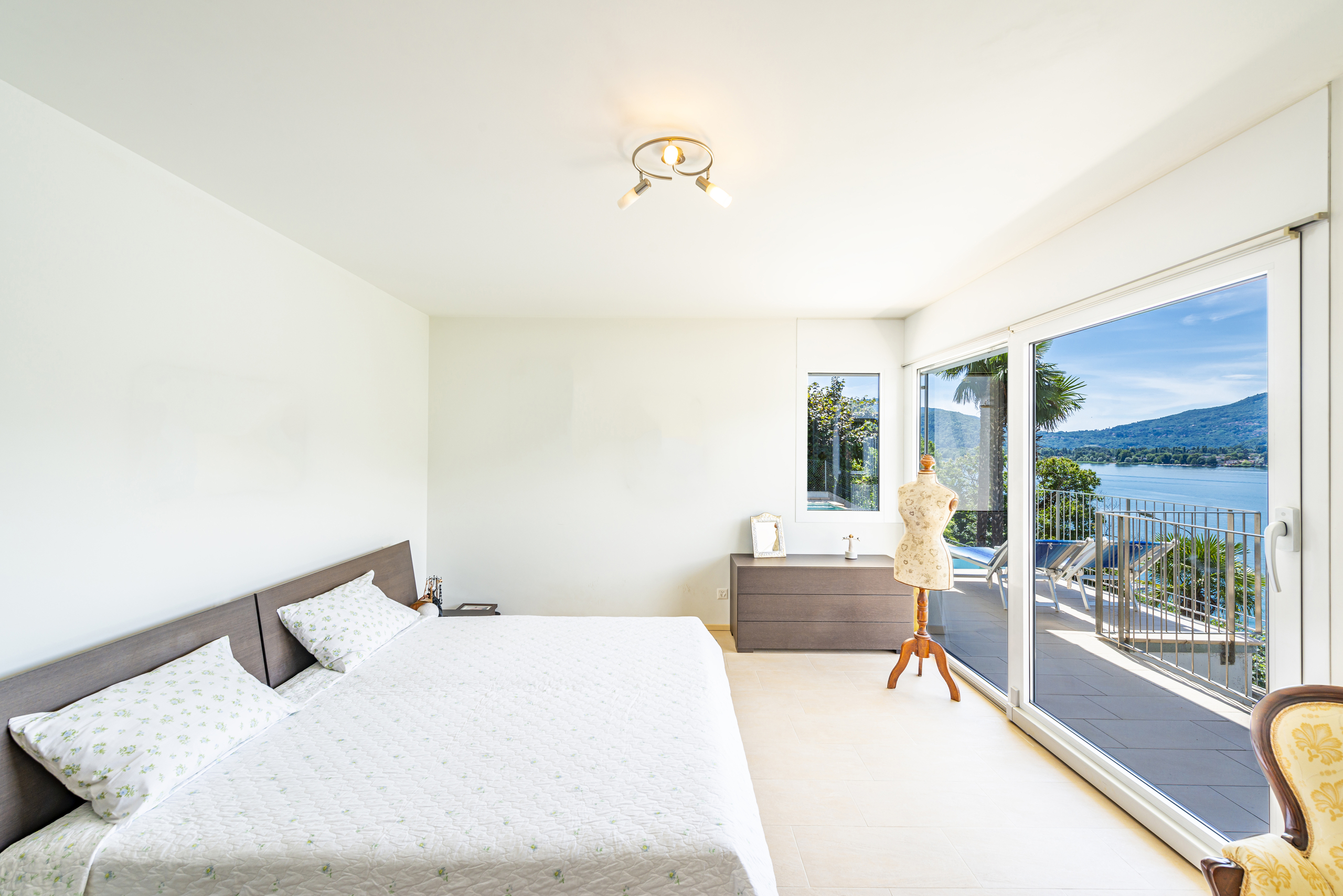 Helles Schlafzimmer mit Balkon- und Seeblick