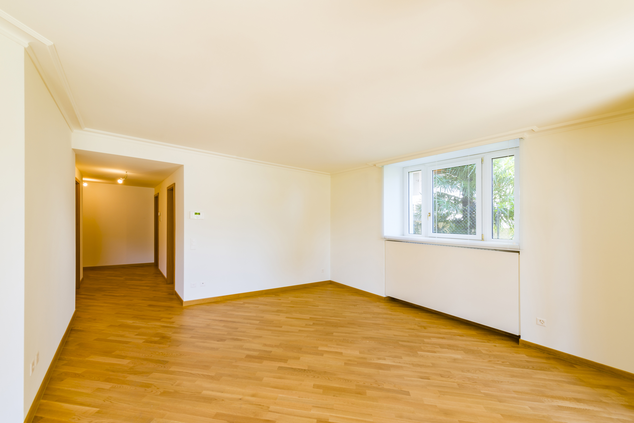 Heller leerer Wohnraum mit Holzboden und Fenster